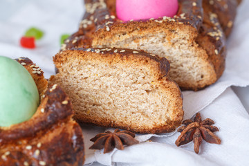 Traditional Greek Easter bread - tsoureki, sliced in Easter decoration with painted eggs and flowers.