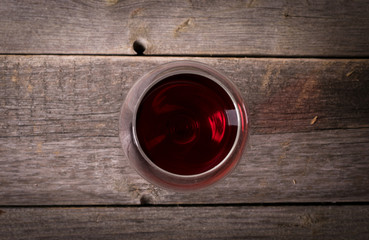 Glass of red wine on wooden table. View from top