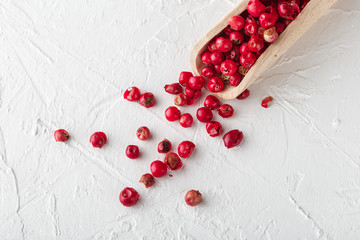 Pink pepper scattered on white textured background