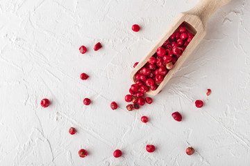 Pink pepper scattered on white textured background