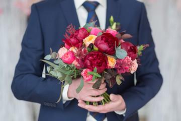 Stylish groom holding a wedding bouquet