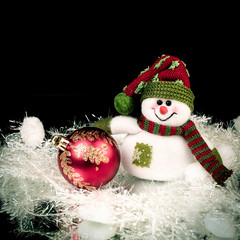 Fototapeta na wymiar fun toy snowman and Christmas ball on a black background.