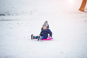Fototapeta na wymiar Cute little girl with saucer sleds outdoors on winter day.