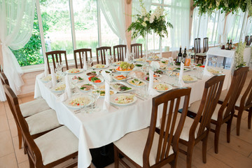 Beautiful wedding floral decoration on a table with catering food in a light restaurant hall with white tablecloths