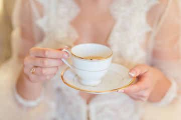 Cup of tea or coffee in female hands close up at morning