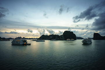 Halong bay at sunset with tourist cruise ships and rocky islands. Popular landmark, famous destination of Vietnam