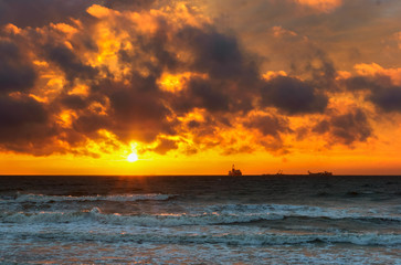 Sunset over the sea. Reflection of sunlight in the sea waves. Red sky in the rays of the sunset.