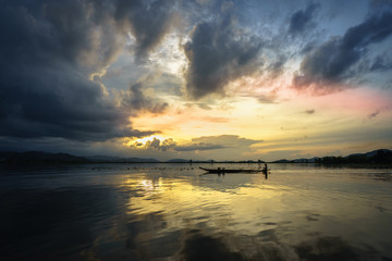 Fototapeta na wymiar Lake with wooden boat at sunset in Vietnam