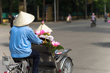 Cyclo (pedicab) driver wears conical hat on Hanoi street
