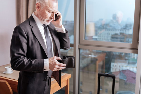 Bill Please. Calm Pensive Senior Man Holding His Wallet While Standing And Talking On The Phone 