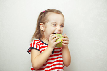 Kid with cute hairstyle holding and eating green apple