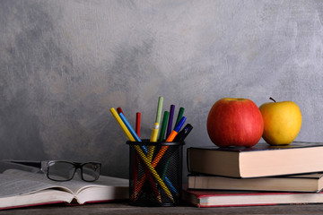 Group of school supplies and books on wooden table over a grey background