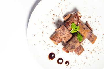 Chocolate crepes with banana filling close-up on a white plate. horizontal