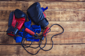 The image of boxing gloves, a skipping rope, taping bandages on a wooden table