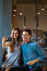 Couple In Cafe Taking Photos On Phone.