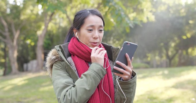 Woman talking on cellphone with earphone, making live stream, call a video on smart phone at outdoor , woman wearing winter jacket