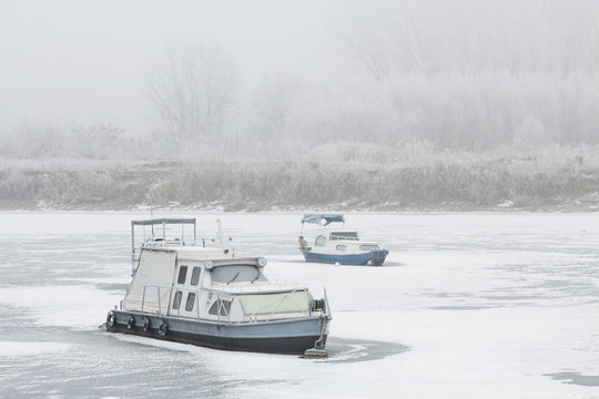 Two old boats wrecked in a frozen river Tisa near Becej, Serbia. Winter time
