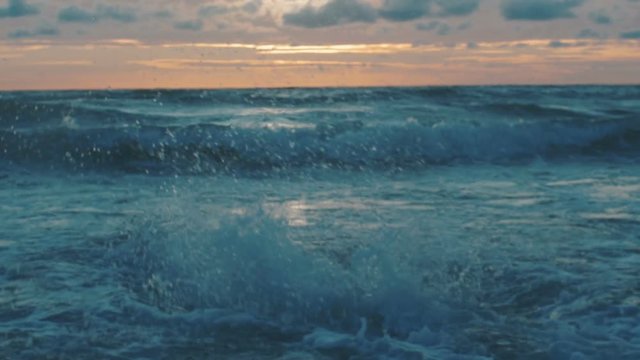 Sportsman swimming in wawes at sunset on beach.