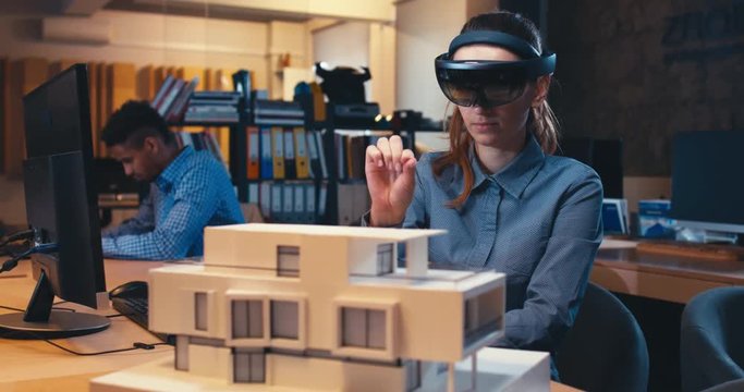 Caucasian female professional architect using augmented reality AR hololens headset to work on a house project. 4K UHD RAW edited footage