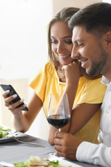 Couple In Love Looking On Phone Having Dinner In Restaurant.