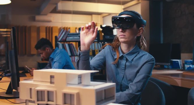 Caucasian female professional architect using augmented reality AR hololens headset to work on a house project. 4K UHD RAW edited footage