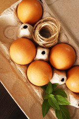 Eggs in a box on a dark background, basil and rope