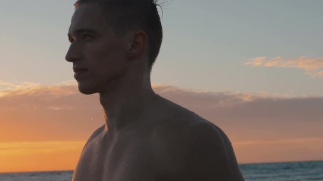 4k of handsome muscular man walking at sea looking away