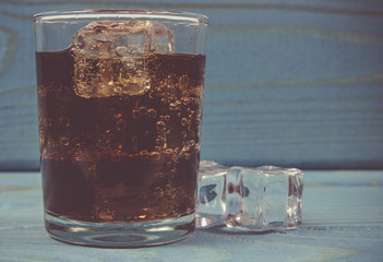 Sweet, fizzy drink with ice on a blue background.