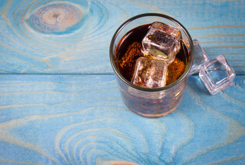 Sweet, fizzy drink with ice on a blue background.