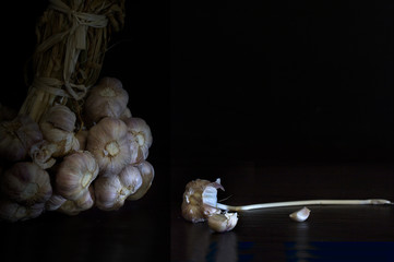 Bunch of garlics and shatters of garlic on dark and dim light background