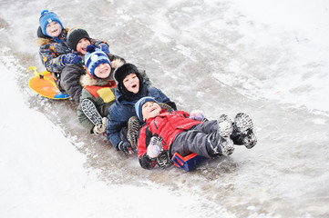 children having fun riding ice slide in snow winter