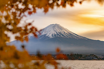 Mt.Fuji in autumn on sunrise at lake Kawaguchiko with blurry maple leave in foreground, Japan
