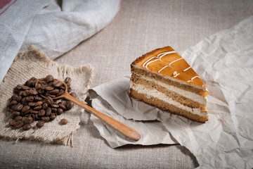piece of cake with caramel lies on paper next to scattered coffee beans