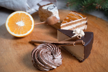  few different slices of cake with the cinnamon sticks and orange on a cutting Board next to pine branch