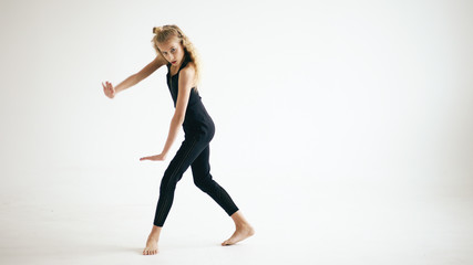 Fototapeta na wymiar Modern beautiful teenage girl dancer dancing contemporary on white background indoors