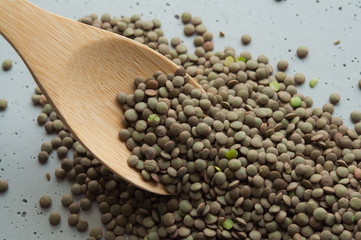 green lentil grains on a wooden spoon