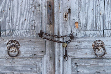 Old wooden door locked with chain and padlock.