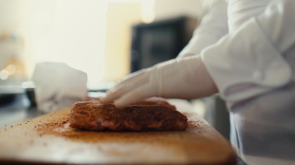 Closeup of professional chef man prepare meat ribs with spice on cutting board at restaurant kitchen