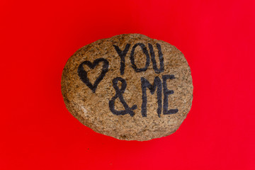 the english writing you and me with a heart drawn on a stone / the writing you and me with a heart drawn on a stone,indicates the love promise of two lovers
