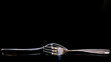 Two metal forks with reflaction isolated on dark background