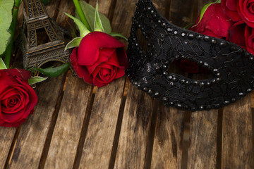 red fresh roses with masque and eiffel tower on wooden table