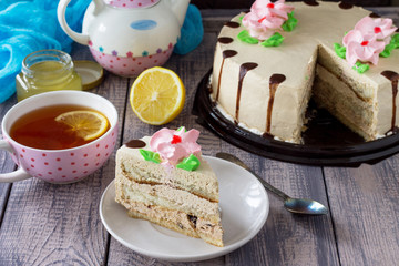 Delicious birthday cake with lemon бискуит, butter cream, walnut and chocolate icing. Serving of a festive table.