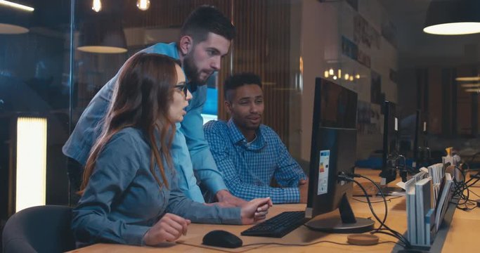 Diverse group of three multiracial colleagues professionals brainstorming together while discussing a project on computer screen. 4K UHD