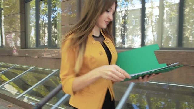 Happy business woman throws over next important documents from folder. Business woman with green folder goes to business district
