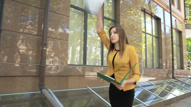 Evil business lady throws out important documents from folder on street. Business woman with green folder goes to business district
