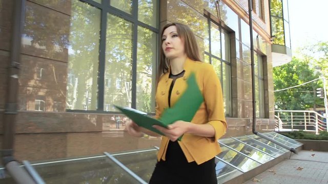 Business lady is angry and throws financial documents out of green folder. Business woman with green folder goes to business district