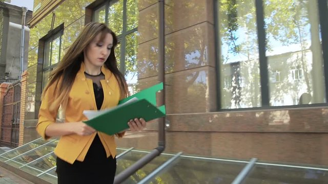 Business lady in yellow jacket is angry and throws financial documents out of green folder. Business woman with green folder goes to business district