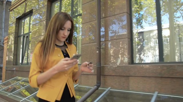 Woman in yellow jacket makes online purchase using phone. Business woman makes purchases on internet