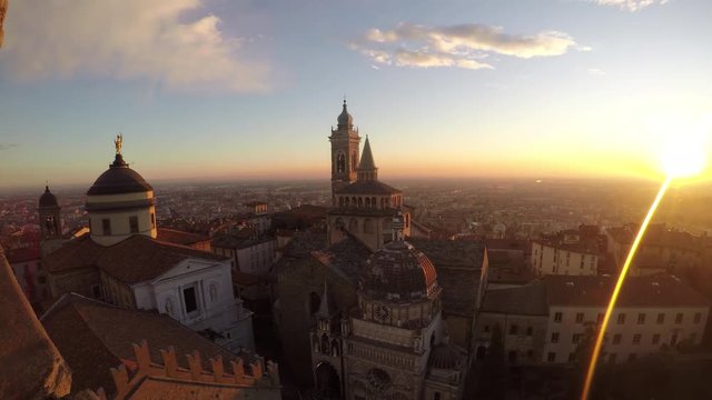 Bergamo, Italy. The old city. Timelapse aerial view of the Basilica of Santa Maria Maggiore and the chapel Colleoni during the sunset. In the background the Po plain