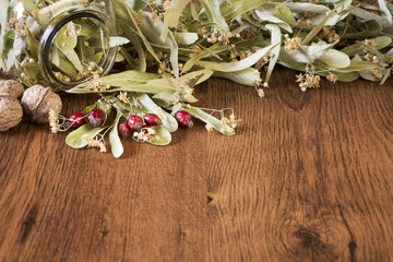 Healthy concept view of dry linden flowers, red rose hips and nuts on wooden background.